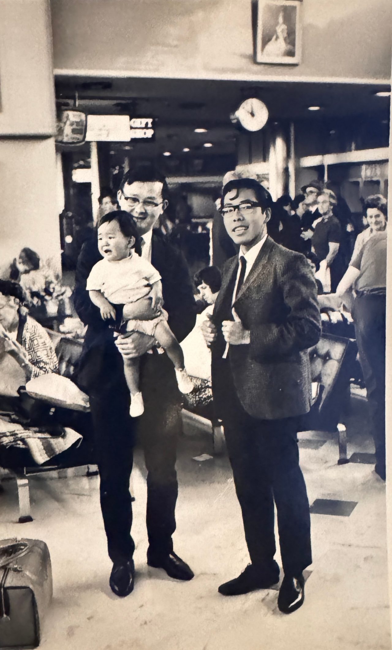 Mr Joseph Yong (left) holds his son while they wait with a friend at the airport for a flight home on their last day in Christchurch.