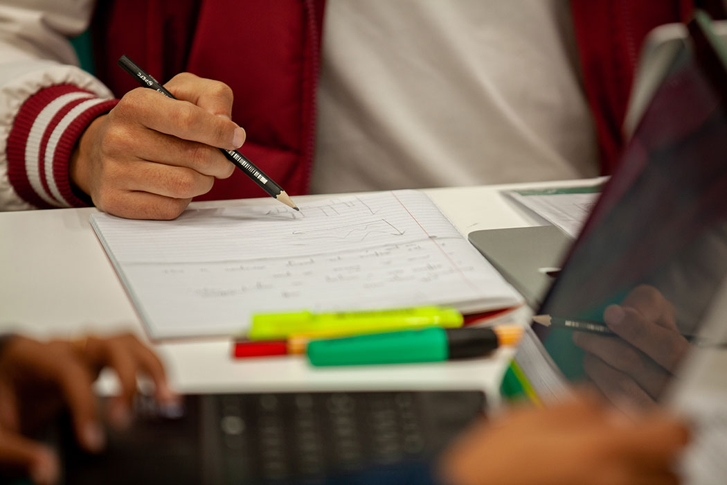 UC student drawing graph sketches on a notepad from a list of statistical data.